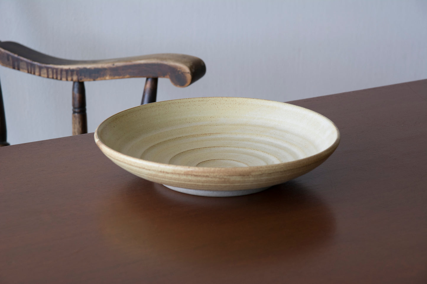 Modern rustic dining decor with a large handmade yellow ceramic salad bowl