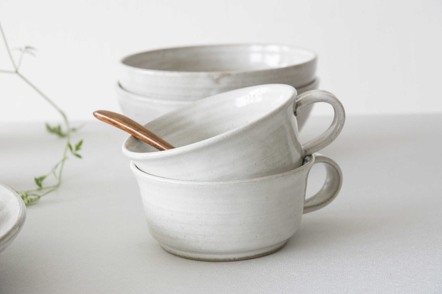 Stack of white ceramic mugs on a light background