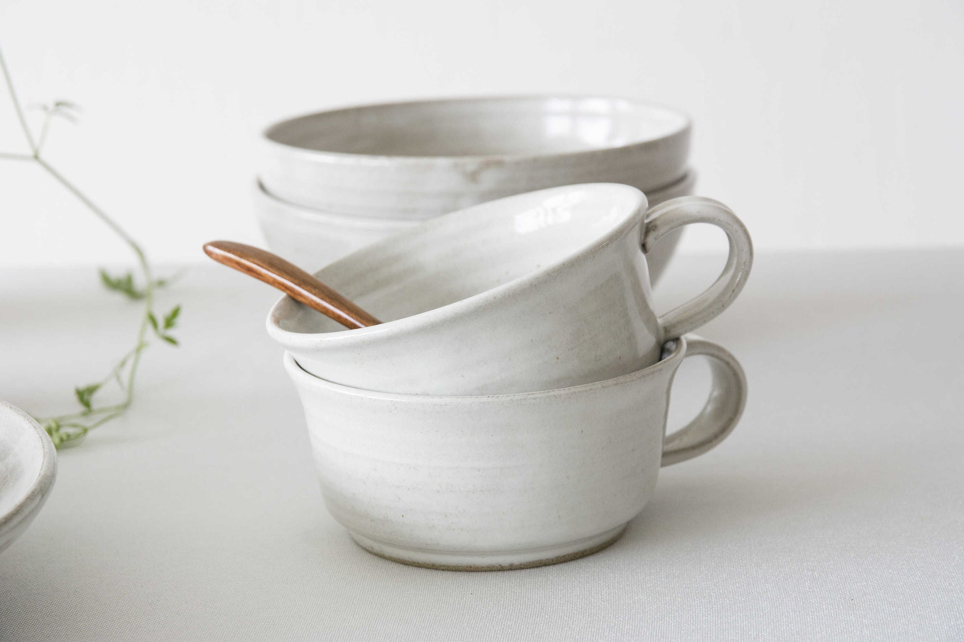 Stack of white ceramic mugs on a light background