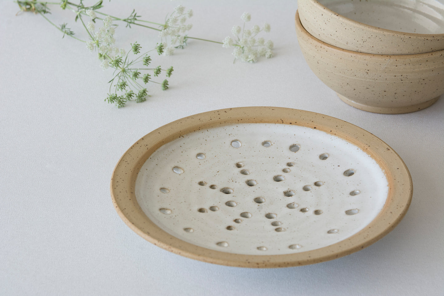 Ceramic perforeated plate dish with textured surface on a light background