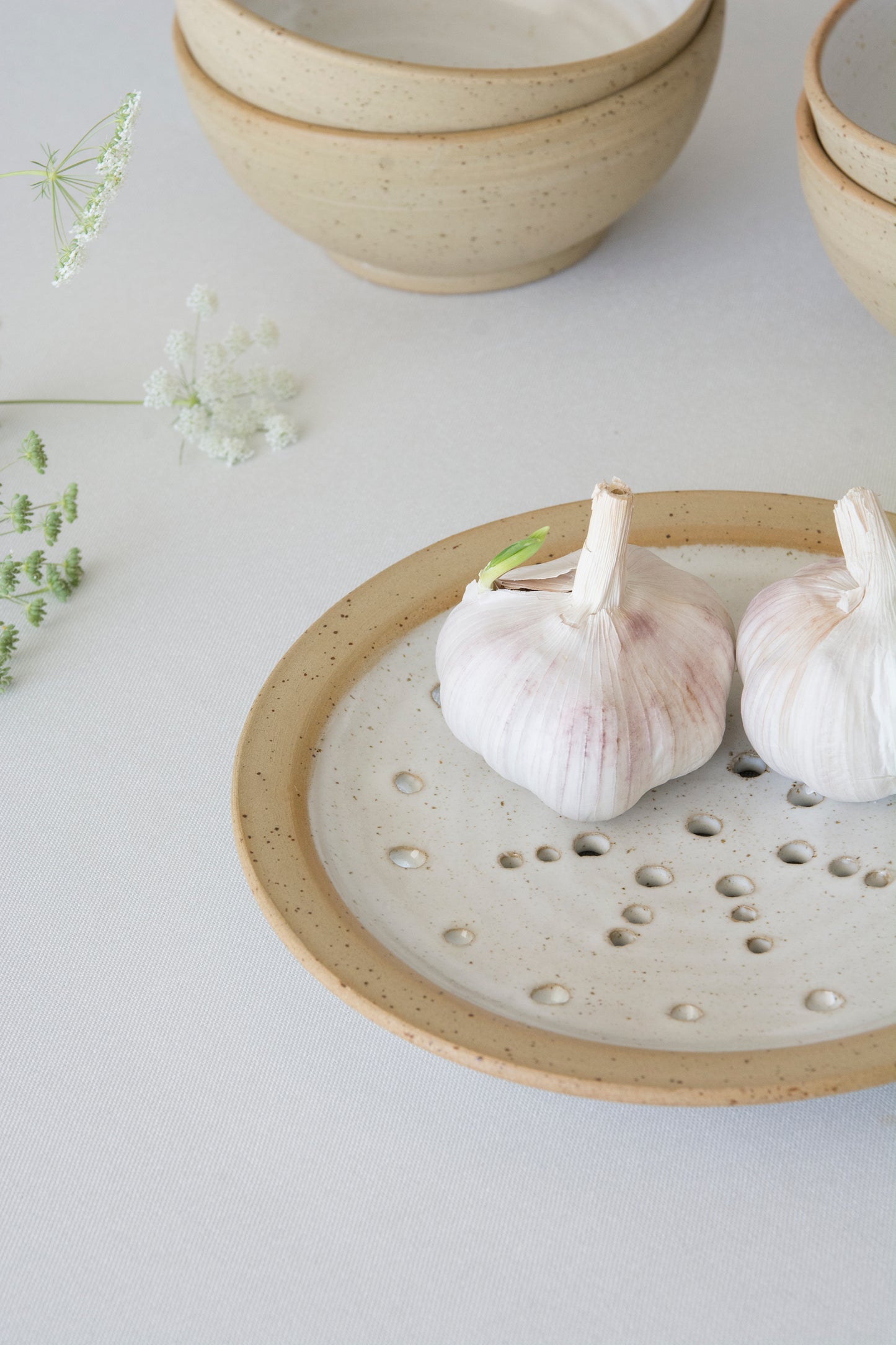 Two garlic bulbs on a ceramic stranier plate with a light background