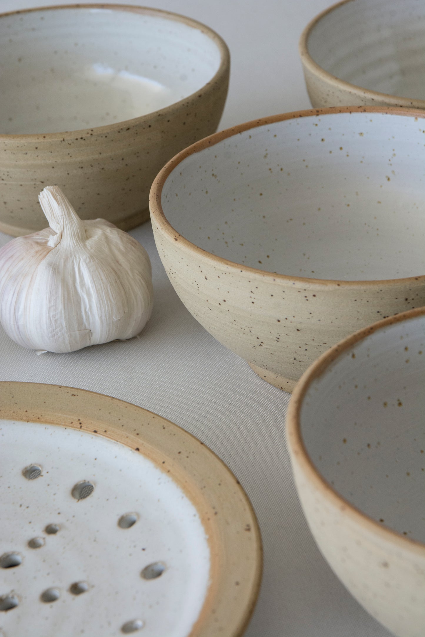 Set of ceramic speckled clay in ocher yellow clay bowls with speckled texture on a light background