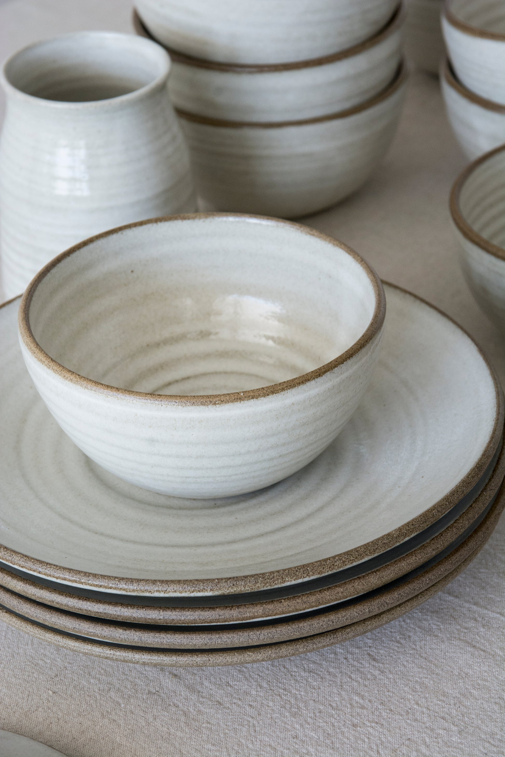 Artisan stoneware bowl in natural white glaze, textured with subtle throwing rings.