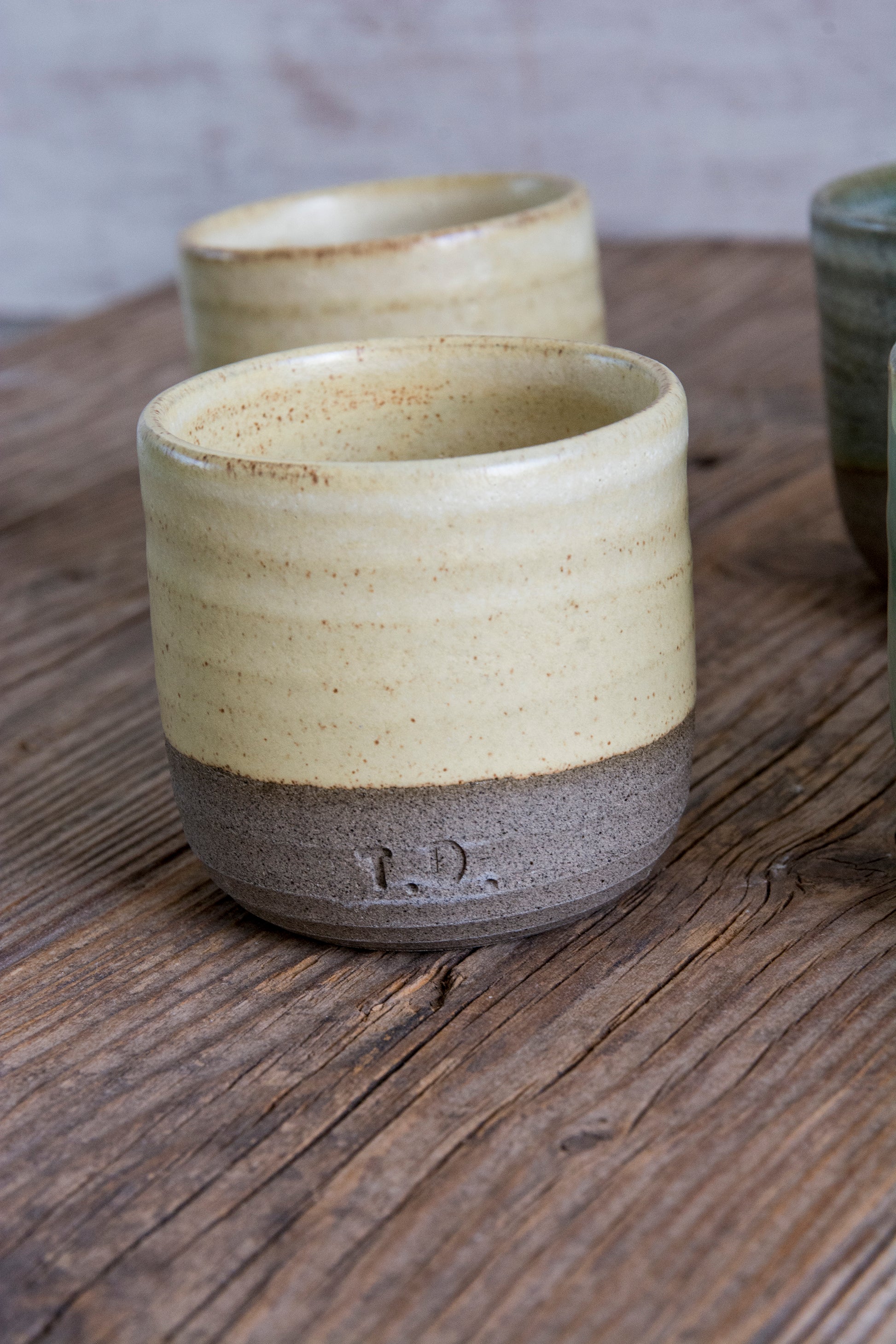 Two ceramic cups with a rustic finish on a wooden surface
