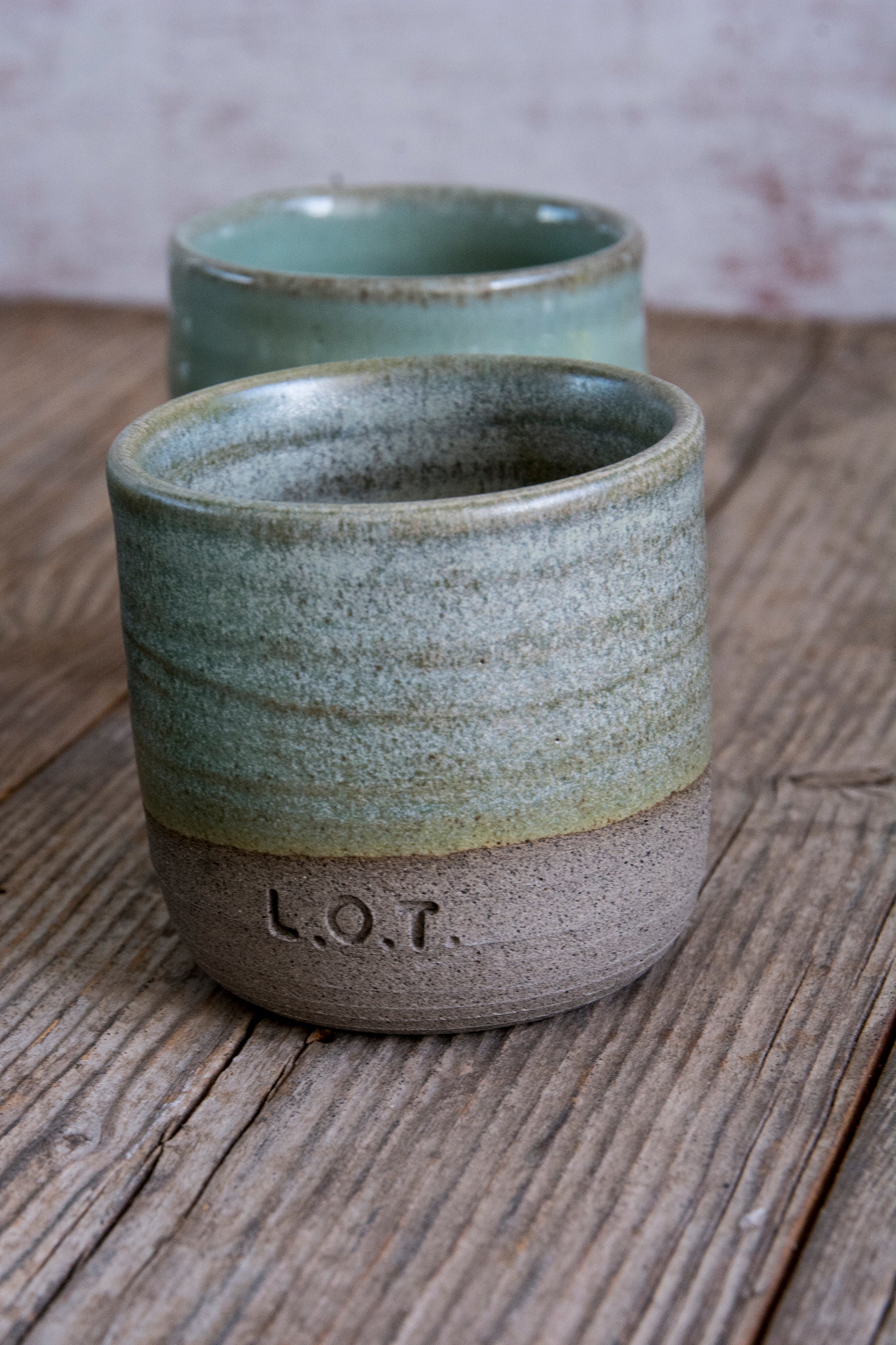 Two ceramic cups on a wooden surface with a blurred background