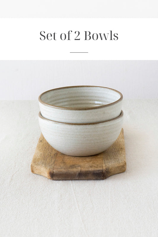 Handmade ceramic bowl with rustic white glaze and exposed clay rim, part of a matching dinnerware set