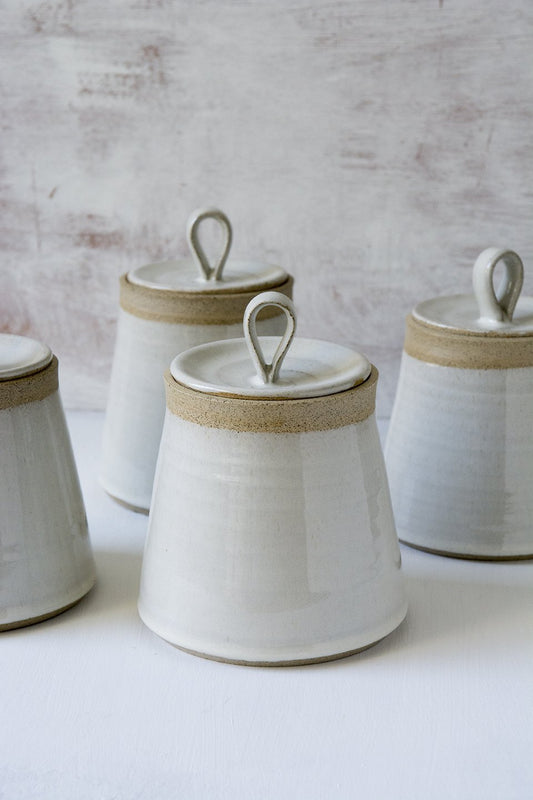 Earthy toned pottery jar with cotton swabs, placed on reclaimed wood countertop
